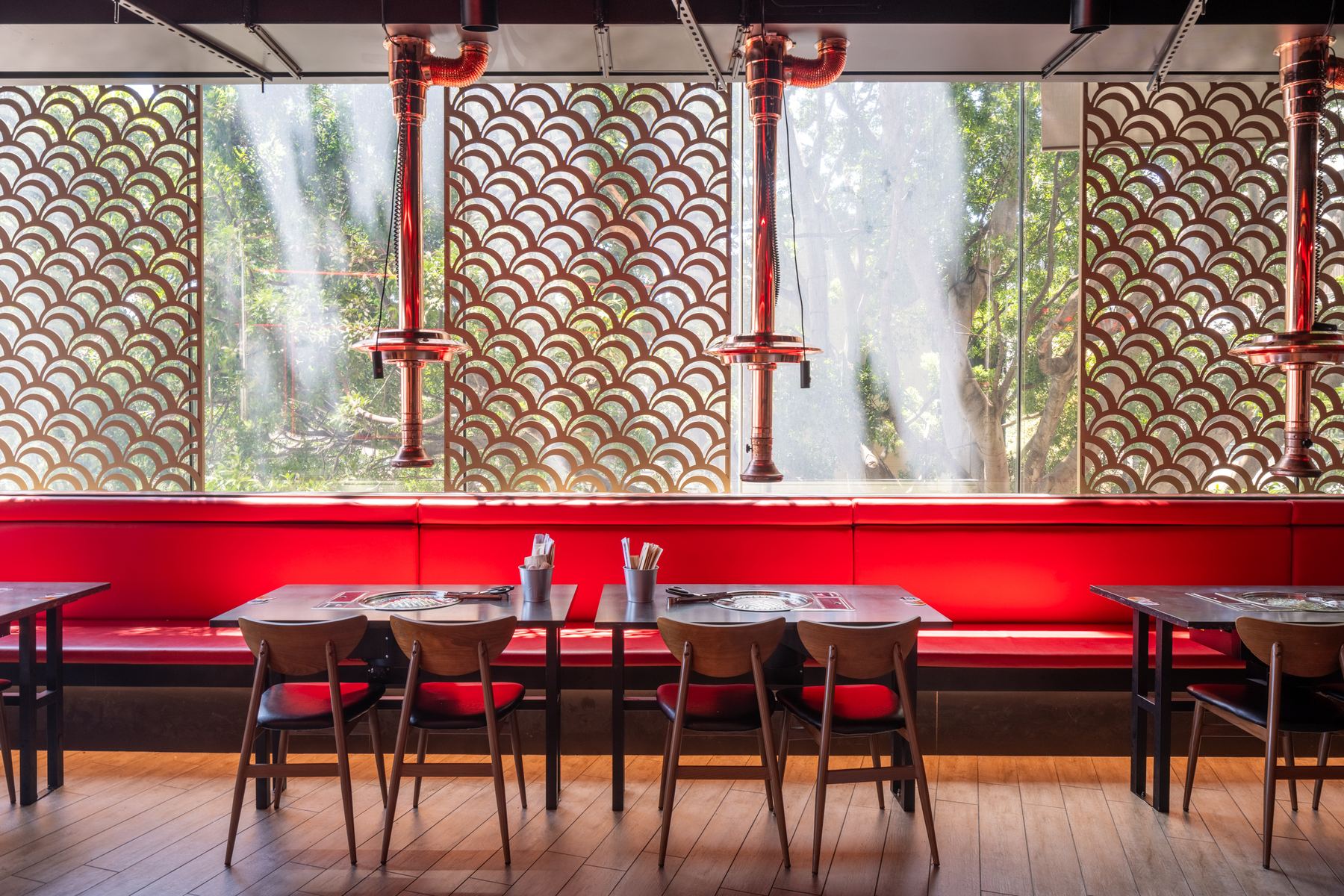 Dining booths in daylight beneath patterned window screens