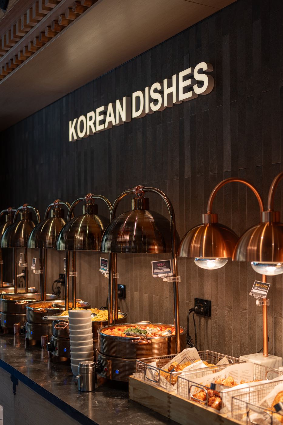 Korean Dishes signage above a row of copper carvery lamps