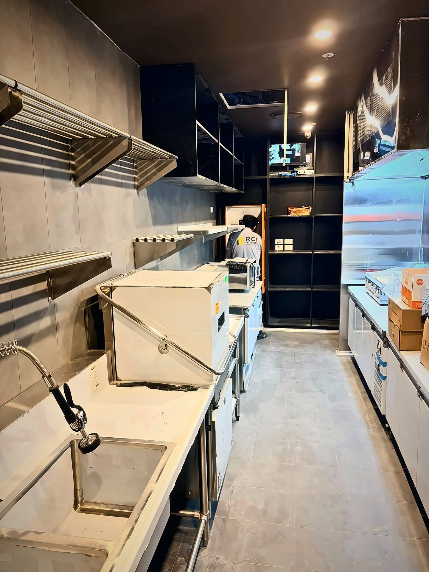 Back-of-house kitchen with stainless shelving, wash-up sink and refrigerated benches