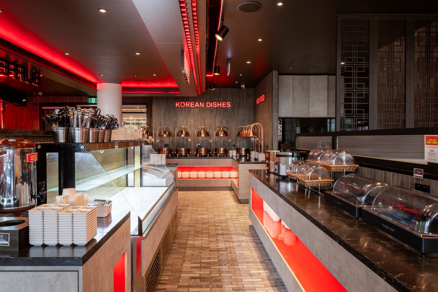 Buffet servery aisle in stone and stainless with copper carvery lamps and illuminated signage