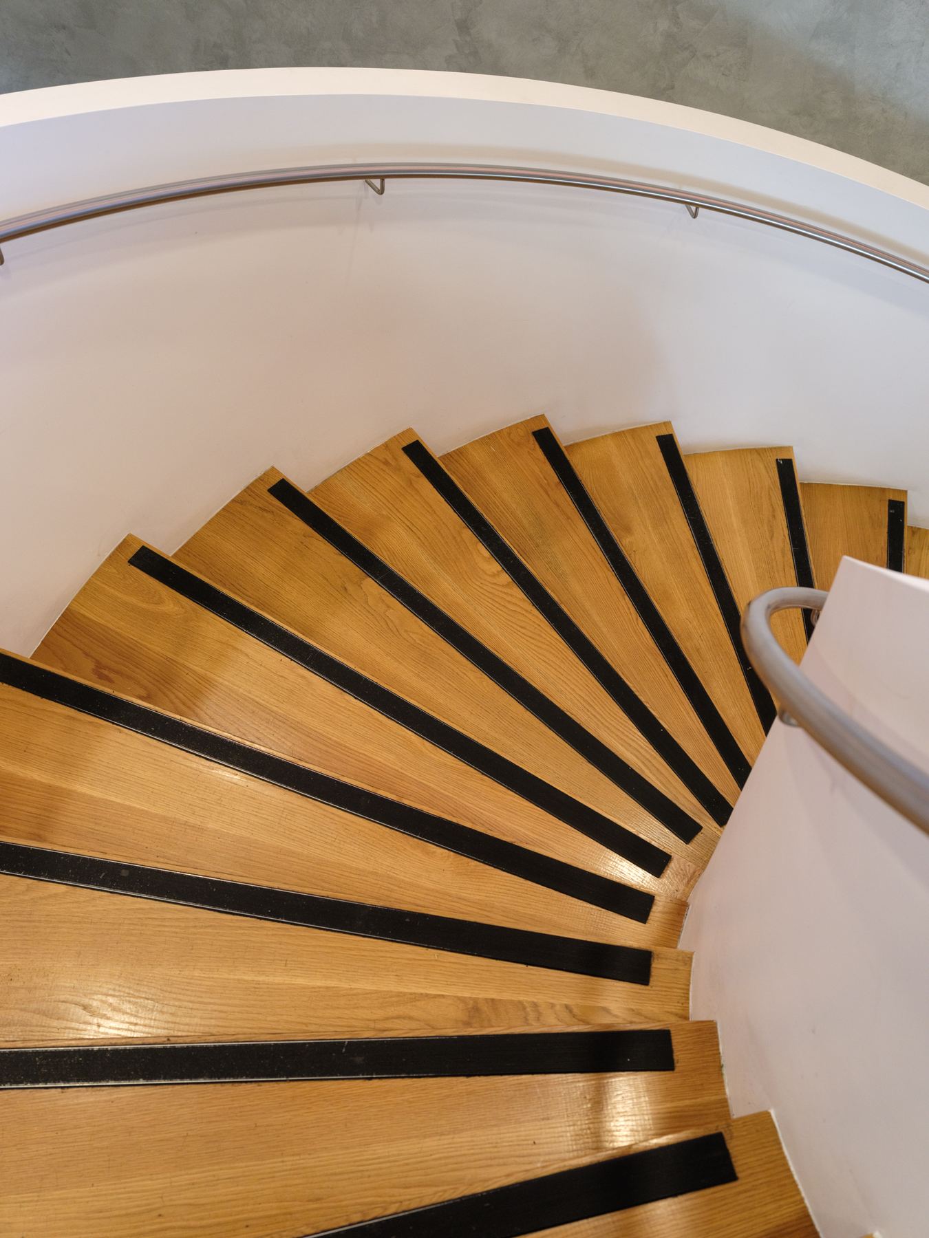 Curved timber staircase seen from above, with black stair nosings